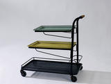 Bar roulant modèle « démon-table » à trois plateaux en métal perforé laqués noir, jaune et vert. Poignée en rotin. 1952, Edition société Matégot - fiftease. H : 76, l : 45, P : 70 (cm)